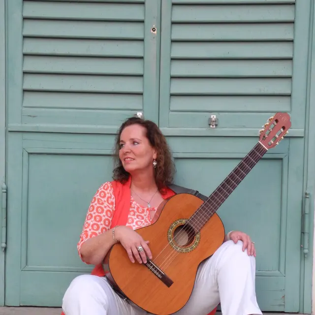 Porträt von Tania Alon mit Gitarre vor einer grünen Fensterlade